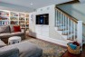 Light-Filled Basement Remodel – Den with Built-In TV and storage under stairs.