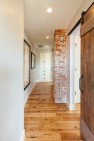 Under the Eaves – Second Story Remodel – Hall with exposed brick chimney and barn doors.