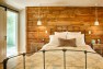 Under the Eaves – Second Story Remodel – Master bedroom with rough wood accent wall.