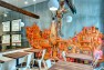 Oasis Tea Zone Capitol Hill – Orange space man installation on concrete wall. – Retail Café Design