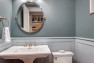 Powder room with oval mirror and pedestal sink.  – Gut and Remodel of a 1960s-era Home – Sound Landing – Board & Vellum
