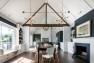 A dining room and kitchen with gabled ceilings with trusses. – Architecture by Board & Vellum.