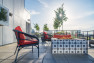 A fire pit on a rooftop with a sun flare shining through the trees.