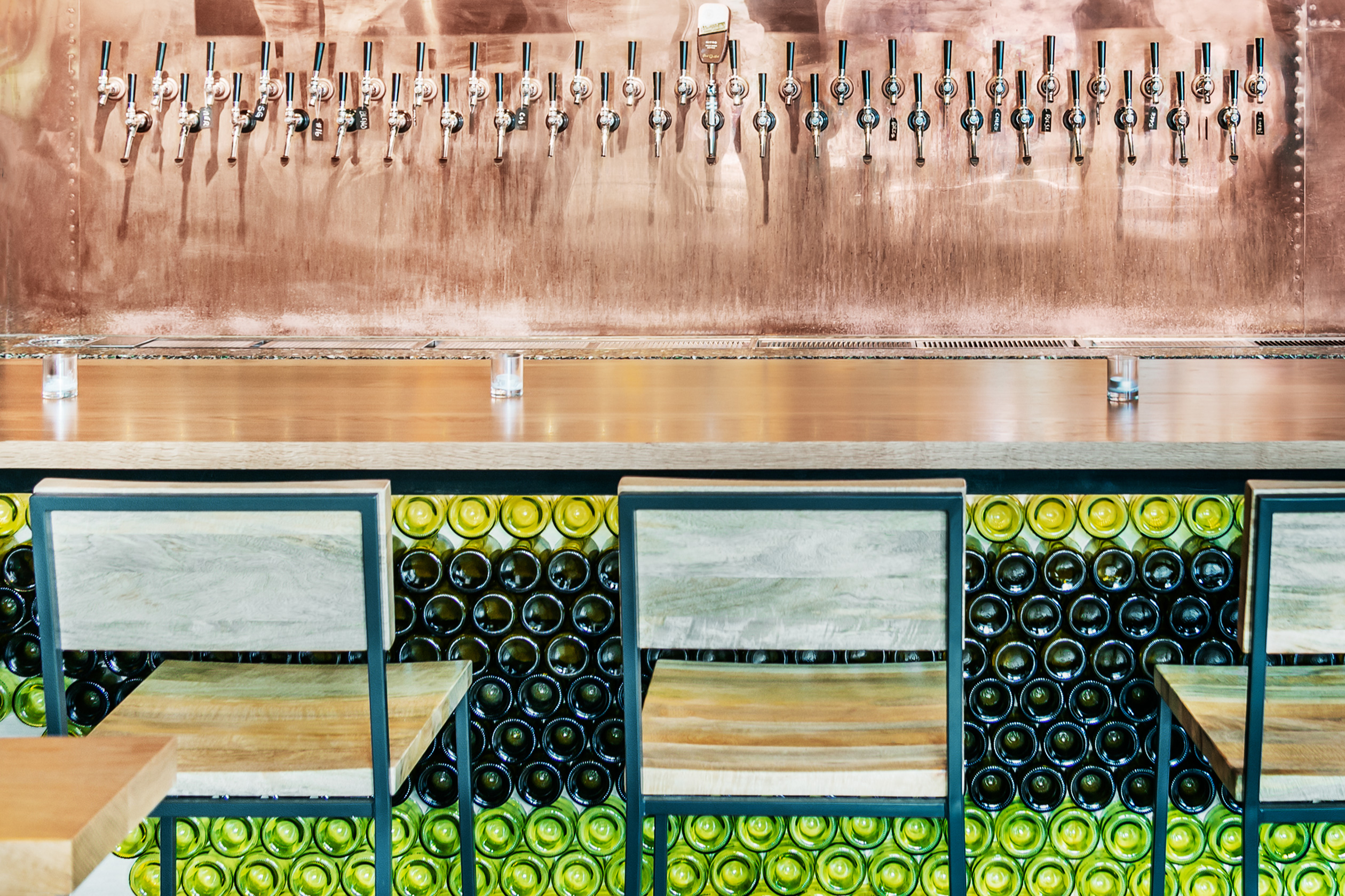 Salvaged wine bottles on the face of a bar are a creative cost-saving tip.