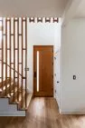 A custom railing and wood screen are detailed with a midcentury modern look in the entry foyer of this home.