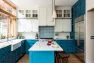 A contemporary kitchen with painted blue cabinets and tile backsplash lending it a California feel.