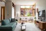 A living room with midcentury style, with a couch, coffee table, and sitting area under large windows.