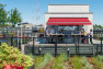 A rooftop bar with a red awning, surrounded by a roof garden.