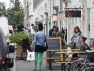 Pedestrians in the public realm, walking along a sidewalk with shops and cafés.