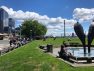 Public life: people enjoying the lawn, benches, sculpture and view at Victor Steinbruck Park on a sunny day.