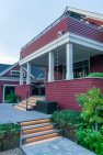 A large, covered back porch with steps down to a back deck and patio.