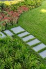 Concrete pavers turn the corner as a path through the green lawn.