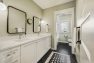 Shared hall bathroom with double sinks and a patterned tile floor.