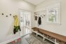 A mudroom in a Craftsman home with hooks for coats and a bench with cubbies for shoes underneath.