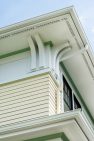 A detail shot of the exterior historical elements on the roofline of the yellow home with a second-story addition.