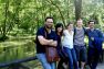 Tom and a group of his friends smile for the camera on a bridge over a calm, green river.