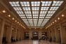 Looking to the a grand hall at Toronto, Canada's Union Station. There are people walking through on their way places. Windows are on the roof letting light into the hall.