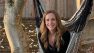Kristin is sitting on a hammock smiling at the camera.