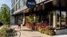 Outside the Lucille on Roosevelt in Seattle, WA, a jogger runs along the sidewalk, which is lined with growing and colorful plants.