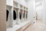 To the left, a large bank of white cubbies and drawers create bench seating. There are black coats hanging on the cubbies.
