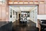 A large opening in the kitchen, framed by built-in cabinets, opens to a dining area with a long central table.