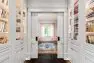 A large hallway lined with built-in shelving full of books ends in a set of pocket doors, behind which is a study.