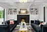 The living room at the Snohomish Estate. Two dark blue couches flank a narrow coffee table. At the center is a black fire place surrounded by bright white built-ins with a display of ceramics and art.