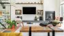 A living room with a glass wall to the left and a coffee table facing  a hearth and TV at the center.