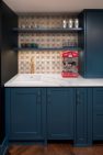 A small kitchenette with a compact sink, open storage, and dark blue cabinets.