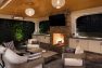 An outdoor lounge with a fireplace, seating, and television.