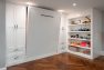 A wall of built-in cabinets with a Murphy bed slightly open. On the right is open shelving with games on it.