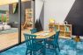 A photo of the interior of a multifamily residential amenity clubhouse. Focuses on a play room for children, furnished with blue carpeting, a bookshelf, a table, and toys like wooden boats.
