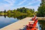 A photo of a floating dock over the surface of a lake. Includes red deck chairs and a ladder for swimmers.