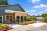 A photo of the exterior of a multifamily residential amenity clubhouse. Includes outdoor landscaping and a view of the adjacent lake.