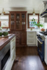 A custom, wood, built-in display case in a traditional kitchen. The built in display case has glass on the front doors as well as the sides to allow light to filter through from all angles. Traditional Sunlit Kitchen – Custom Home Remodel – Board & Vellum – Architecture & Interior Design