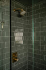 A green tiled shower with a glass door.