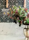 A vignette image with close focus on a set of brass toggle light switches with a clear wall plate, allowing the floral wallpaper to be seen through it.