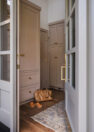 Looking through the front door from the outside into the entry of the home. The door and trim are a soft, light gray-blue, and dusty pink built in shelving is visible inside through the doorway.