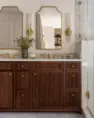 A light-filled primary bathroom’s custom vanity of stained alder with tambour fronts. Serene Modern Tudor — Board & Vellum