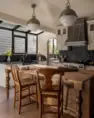 A large kitchen in a remodeled home, with an island of repurposed myrtle wood and solarium wall, which allows ample light into the space and offers a view of the home’s remodeled exterior and yard.