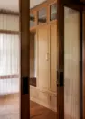 A peek into the home’s flex space through partially closed pocket doors, which feature panels of reeded glass. Beyond the doors, built-in cabinets are visible.