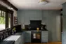 Soapstone runs from the counters up behind the ILVE range, with Willow Boughs wallpaper peeking out above it, a farm sink beneath the window, and brass hardware against the cabinetry. – Tangletown Craftsman – Interior Design for a Craftsman Home – Board & Vellum