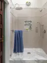 Blush tile lines the shower around a Calacatta niche and marble mosaic floor, under nickel fixtures and a small brass dome light. - Tangletown Craftsman – Interior Design for a Craftsman Home – Board & Vellum