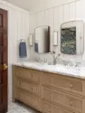 A custom white oak vanity sits beneath a marble counter and backsplash, between brass sconces and curved mirrors, on a marble mosaic floor. - Tangletown Craftsman – Interior Design for a Craftsman Home – Board & Vellum