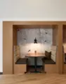 Vertical view of built-in booth seating and warm finishes in Tanager Apartments' lounge. – Tanager Apartments – Board & Vellum