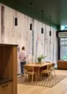 A dining or work table in the amenity lounge in front of wallpaper featuring the trunks of birch trees. – Tanager Apartments – Board & Vellum